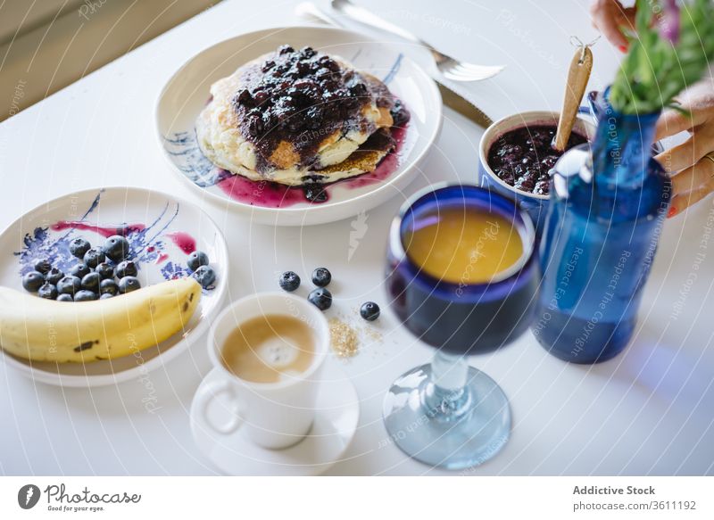 Frau serviert köstlichen Brunch mit Pfannkuchen Frühstück Marmelade Blaubeeren selbstgemacht dienen lecker Lebensmittel Morgen Hand gemütlich Tisch