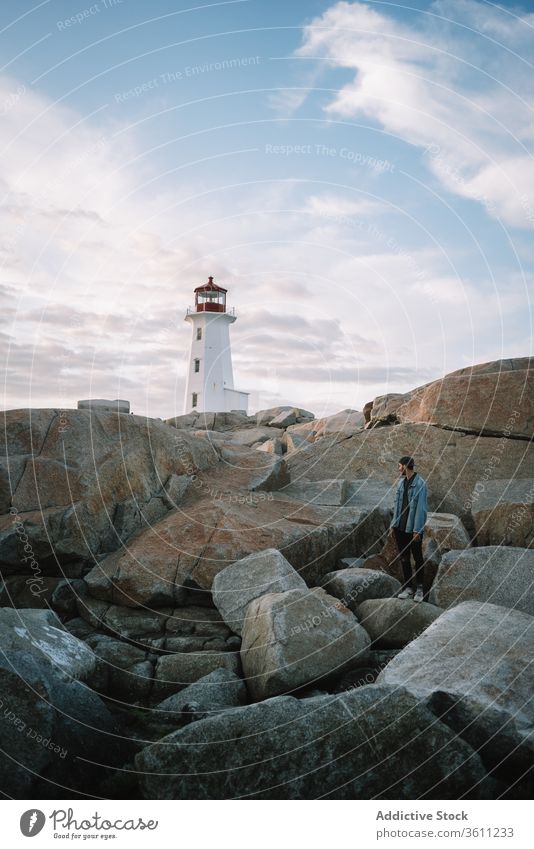Nicht wiederzuerkennender männlicher Reisender bewundert Leuchtturm im Sonnenuntergang Mann bewundern reisen Abend Himmel wolkig Peggys-Bucht Kanada Weg