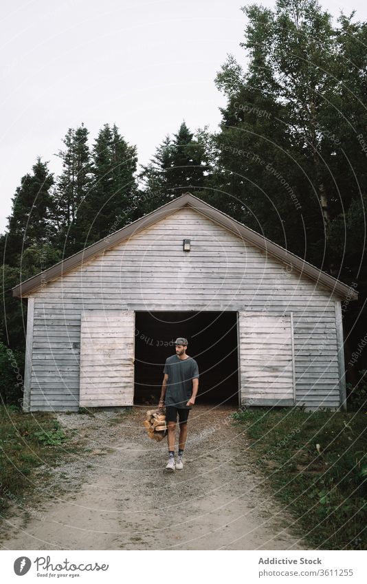 Mann, der einen Stapel Brennholz trägt und aus einer Holzhütte läuft Kabine Haufen Wälder Laden Wald Brennstoff führen Aktivität reisen Quebec Kanada
