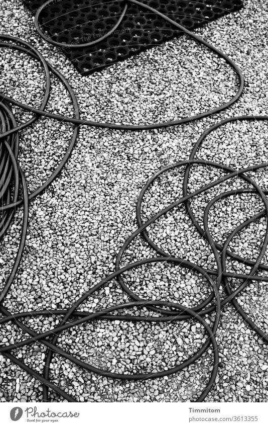 Eine besonders lange Leitung Kabel Boden Split Fußmatte Elektrizität Elektrisches Gerät Schwarzweißfoto Linien