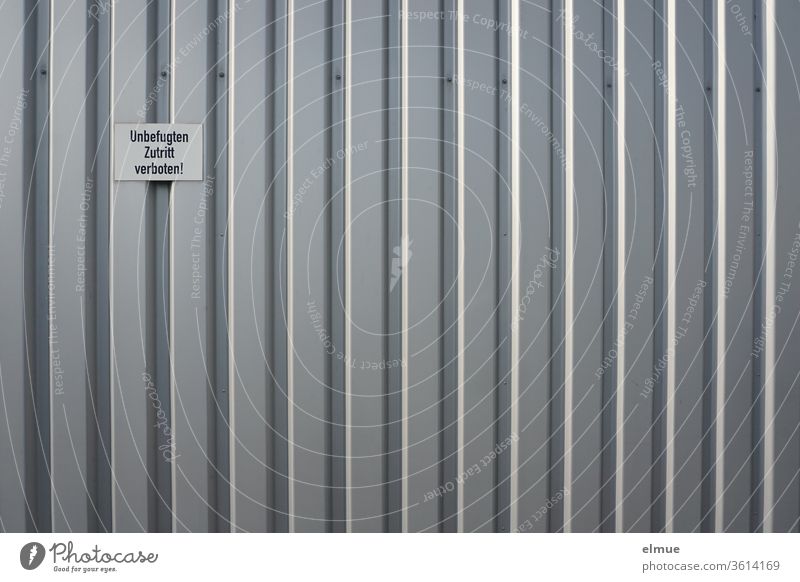 Schild "Unbefugten Zutritt verboten!" an einer grauen Metallfassade Metalltor Fassade Arbeitswelt unbefugt Verbot Streifen geschlossen Schilder & Markierungen