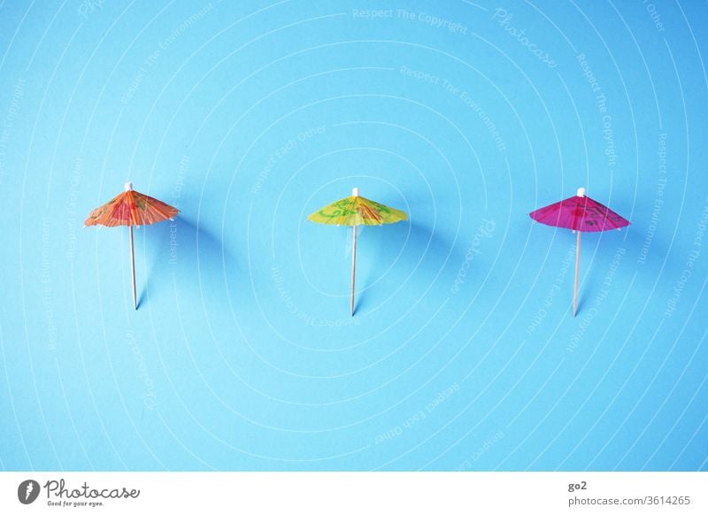 3 Sonnenschirme auf Abstand Sommer Urlaub Papierschirmchen abstand halten Abstandsregel corona orange gelb pink Infektionsgefahr Schutz Gesundheit Schützen