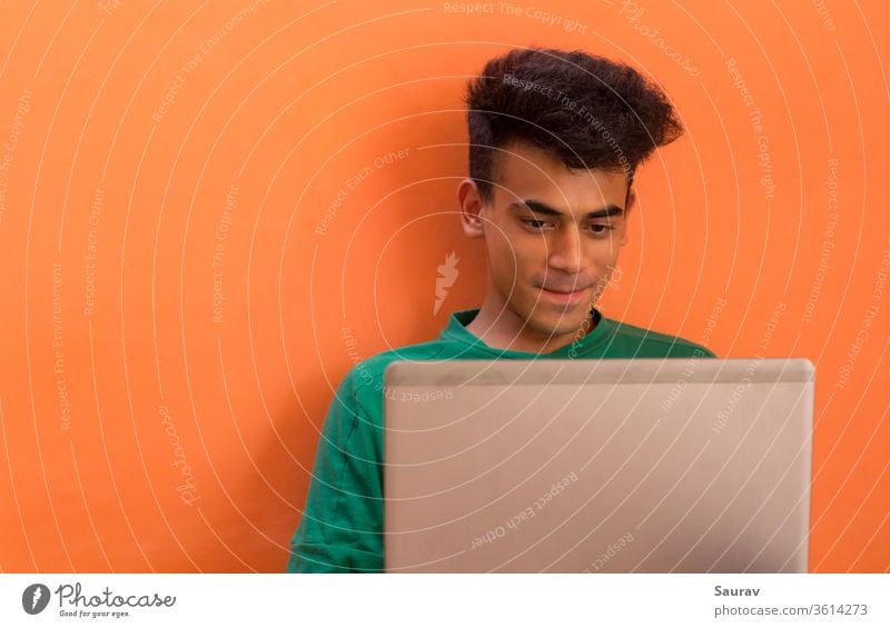 Junger Mann lächelt, während er mit jemandem auf seinem Laptop spricht. tausendjährig Isolation im Innenbereich plaudernd Entertainment in Verbindung bleiben