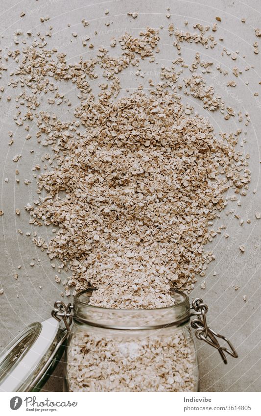 Organische Haferflocken und ein Glas mit Glas auf grauem Hintergrund Lebensmittel Textur Muster weiß abstrakt Korn braun Nahaufnahme Bestandteil Gesundheit