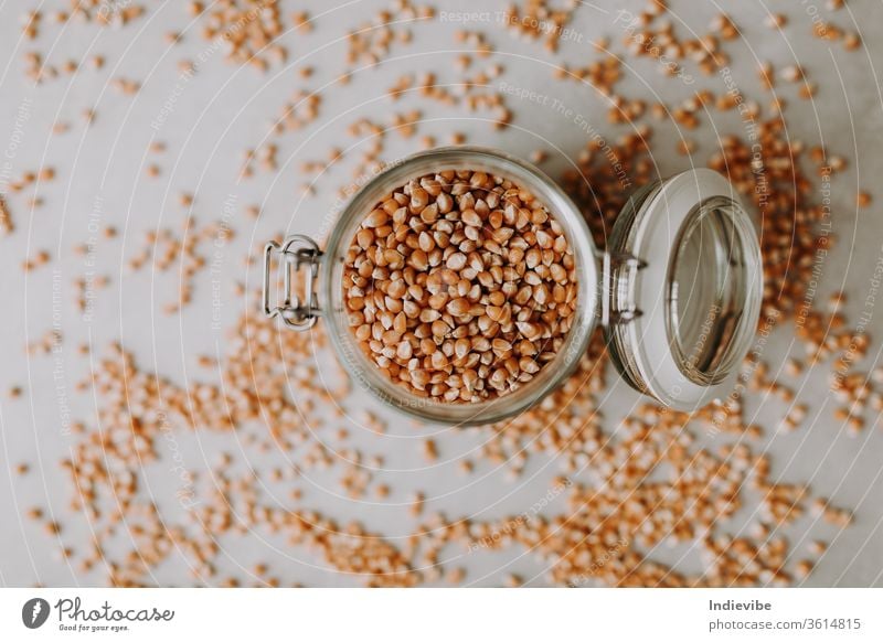 Bio-Maissaatgut und ein Glasbehälter auf grauem Hintergrund Lebensmittel Samen braun vereinzelt Korn Bestandteil trocknen Müsli Gesundheit organisch Haufen