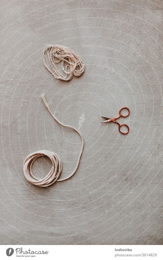 Eine kleine rosa-goldene Schere und ein Stück Seil auf grauem Hintergrund Hobby diy geschnitten Roségold Aktivität Pause Nahaufnahme Konzept Handwerk kreativ