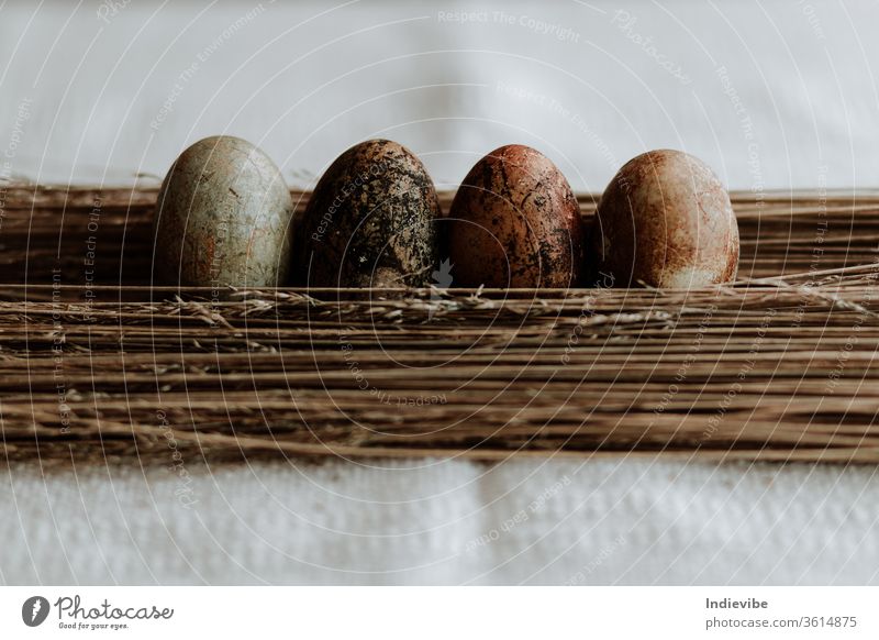 Vier verschiedene Muster natürlich gefärbtes Osterei-Osterdekor auf Strohhintergrund auf einer Leinentischdecke Ostern Ei Dekoration & Verzierung organisch