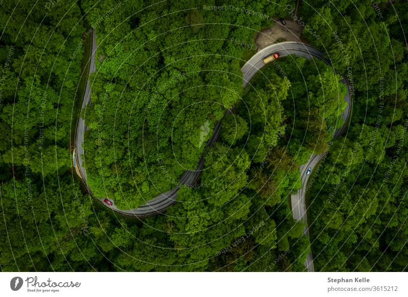 Wunderschöner grüner Wald mit einer kurvigen Straße und Autos aus der Draufsicht Drohnenaufnahme, Luftaufnahme eines S-Kurven-Hintergrundes, der Fahrspaß oder eine Fahrt durch die Natur impliziert.