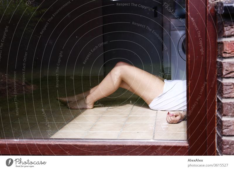 Eine junge Frau liegt hinter einer Glastür in einem Waschraum, man sieht nur die nackten Beine, eine Hand und ein weißes T-Shirt Mädchen schön Haut 19