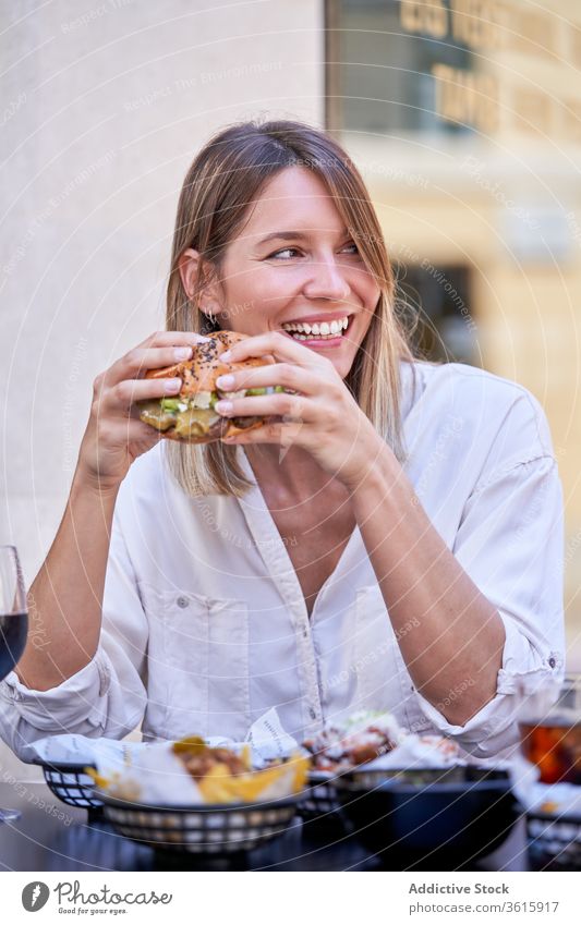 Lachende Frau beim Burger essen mit einem Freund Mittagessen Café heiter Straße Sommer Glück Kommunizieren interagieren Mahlzeit lecker Speise Küche Portion