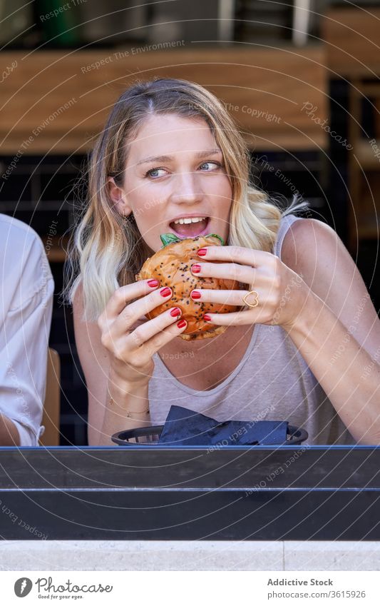 Erstaunte Frau beim Essen im Café Mahlzeit aufgeregt Zusammensein Fenster Lifestyle teilen Burger genießen Sitzung Grimasse Mittagessen expressiv Restaurant