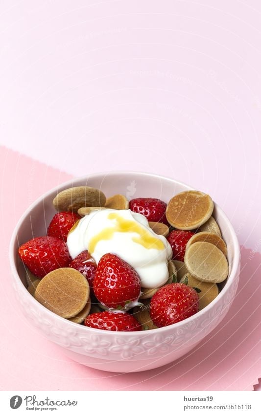 Hausgemachte Getreide-Mini-Pfannkuchen mit Joghurt, Honig und Erdbeeren auf farbenfrohem Hintergrund. selbstgemacht pankakes lecker Lebensmittel erdbeeren