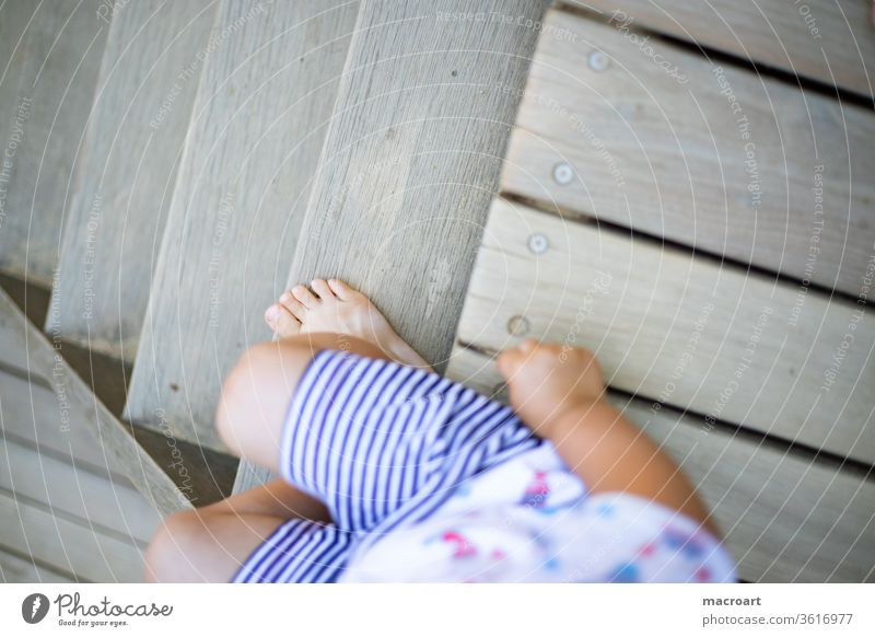 Spielplatz - Kind seitlich angeschnitten auf Holztreppe sitzend holztreppe spielplatz sommer kurze hose klienkind erkennen langeweile ruhe finger kinderhand
