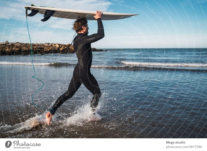 Surfer, der mit seinem Surfbrett ins Wasser geht. Mann Brandung Sport Surfen MEER Meer im Freien sportlich malerisch Küstenlinie Wellen Hintergrund Abenteuer
