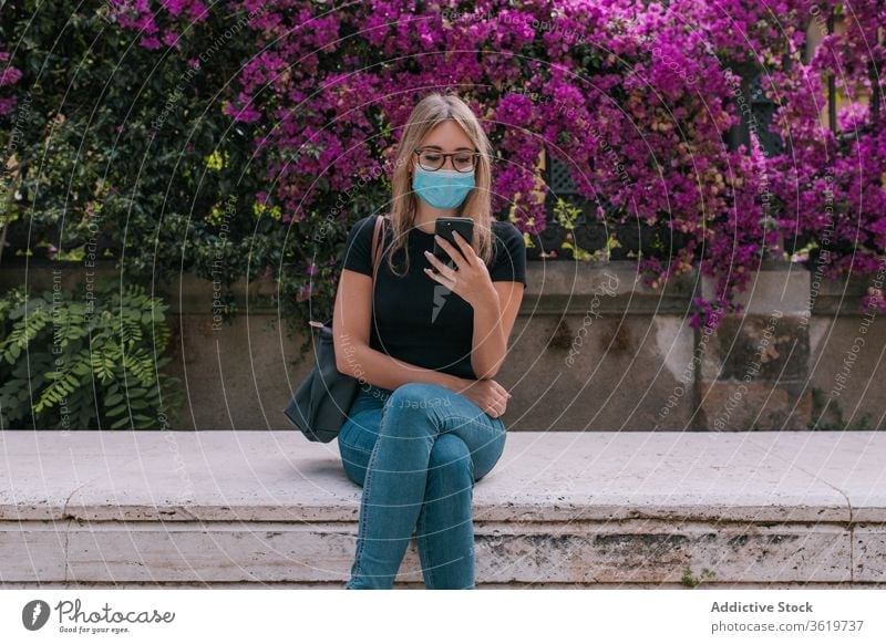Junge Frau, die das Smartphone benutzt und im Freien eine Gesichtsmaske trägt Pandemie Straße Mundschutz Korona Virus Schutz jung Großstadt Person Krise