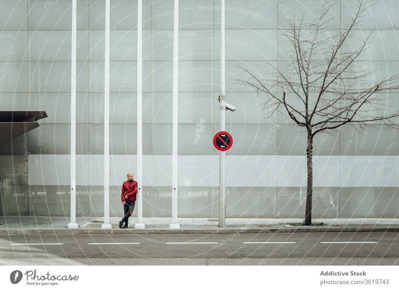 Junger Mann steht in der Nähe eines modernen Gebäudes jung Stil lässig Wand urban Straße trendy verbieten Zeichen männlich Zeitgenosse allein Youngster