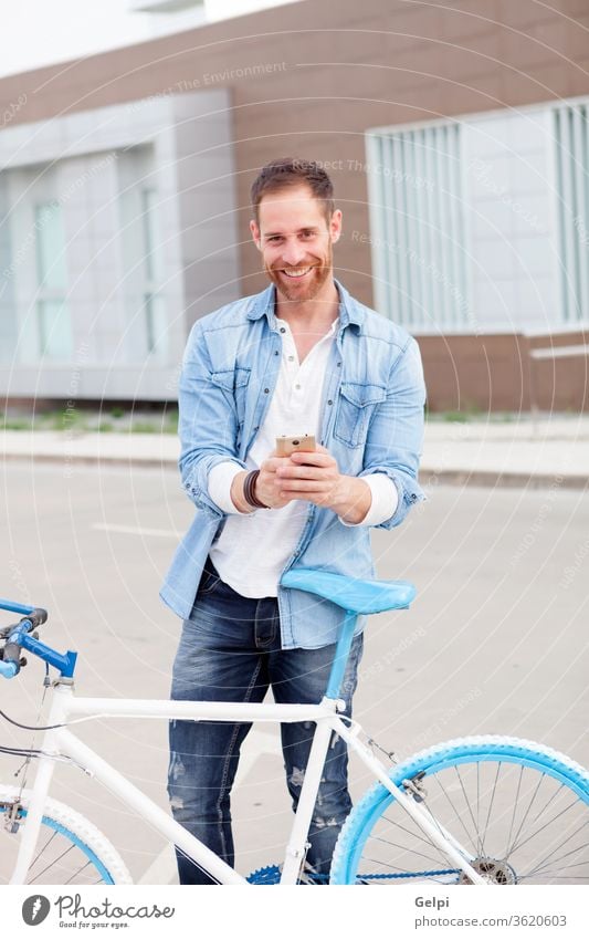 Lässiger Typ neben einem Oldtimer-Fahrrad mit dem Handy im Jeanshemd Telefon jung Mann Mobile urban Lifestyle Büro Business Geschäftsmann Person männlich