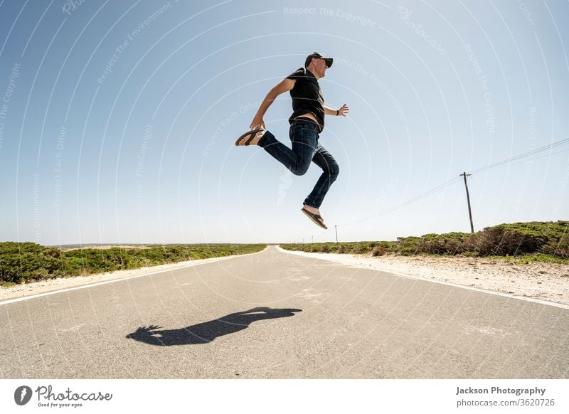 Mann springt fröhlich hoch über die Straße springen Glück Algarve Portugal cabo de sao vicente Kap Heiliger Vinzenz Wildnis oben laufen Perspektive Möglichkeit