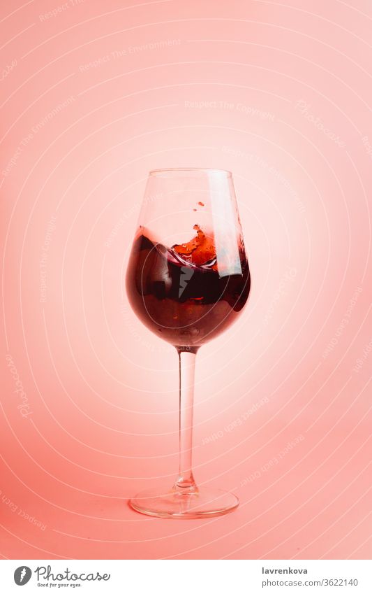 Rotweinspritzer im Glas, dynamisches Bild, selektiver Fokus. Wein Schnaps Gießen Tröpfchen liquide Weingut rot Getränk trinken Feier Alkohol rosa Bewegung