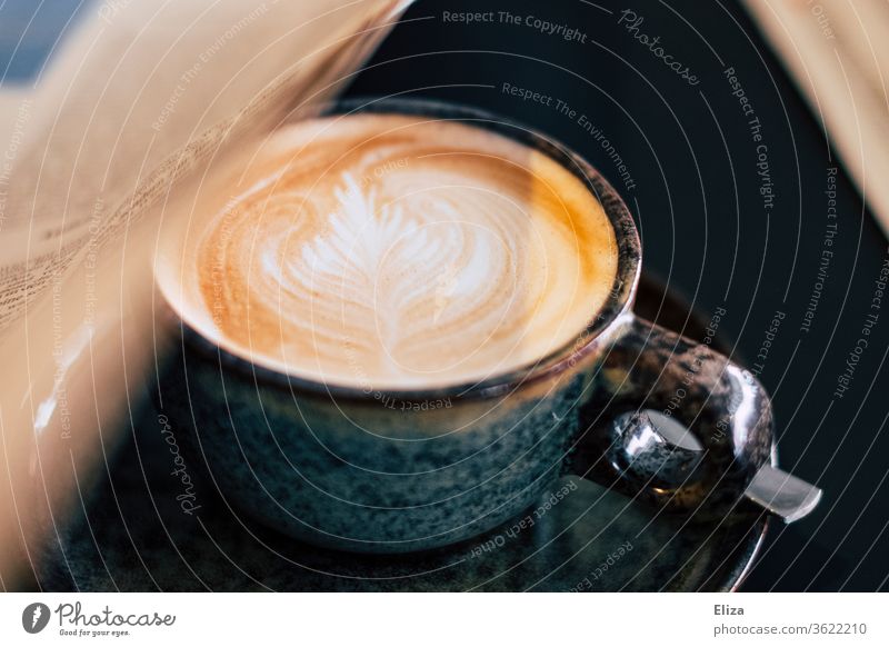 Ein Cappuccino mit einer Zeitung. Morgenroutine. Latte Art Kaffee morgens Kaffeetrinken Zeitunglesen Café Tageszeitung Kaffeetasse Tasse Kaffeepause