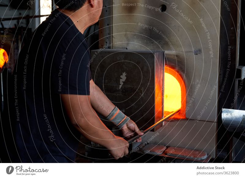 Glasbläser beim Schmelzen von Glas im Ofen Mann Schlag Schmelzofen zerlaufen Blasrohr Werkstatt heiß Handwerk Gerät Kunsthandwerker Fähigkeit Industrie
