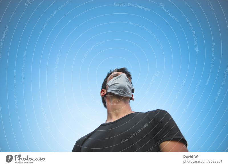 Mann mit Atemschutzmaske schaut nachdenklich in den Himmel denken gedanken ängstlich Maske Schützen Infektionsgefahr Panik Angst Mensch Virus-Ausbreitung