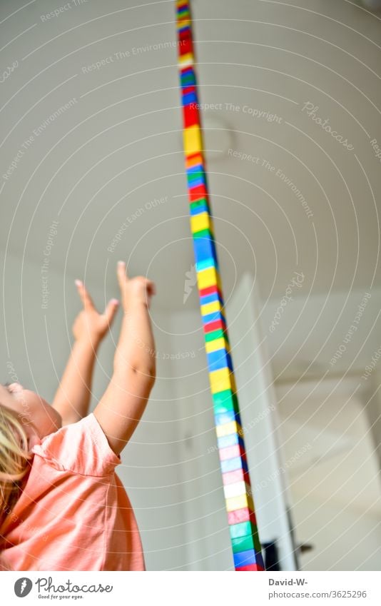 Kind baut mit Bauklötzen im Kinderzimmer einen riesigen Turm und zeigt begeistert mit den Fingern an die Decke bauen Spielsachen Spaß Freude euphorisch Euphorie