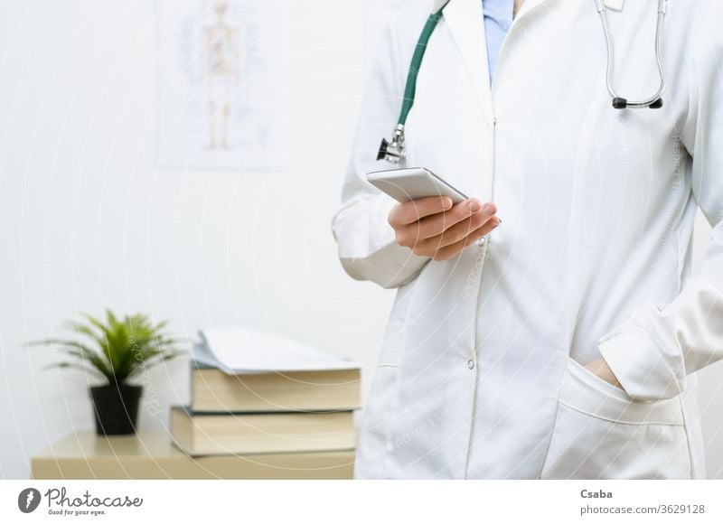 Eine Ärztin schreibt eine SMS auf einem Smartphone Arzt Büro benutzend Technik & Technologie Frau Telefon Hand Funktelefon Texten Tippen Nachricht Beteiligung