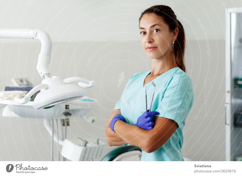 Eine Zahnärztin sitzt auf einem Stuhl und lächelt, während sie Werkzeuge in ihren Händen hält. Zahnarzt Zahnmedizin Büro Pflege Klinik Arzt Gerät Gesundheit