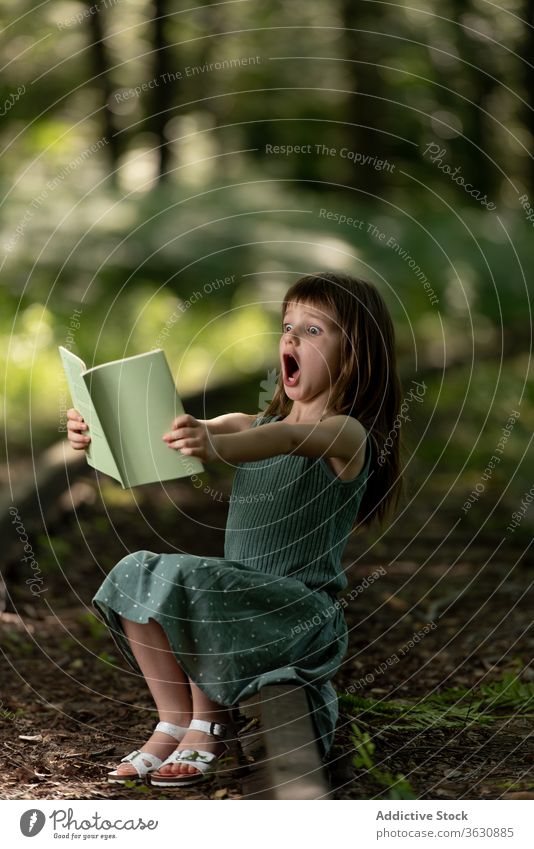 Geschocktes Mädchen liest Buch im Park Schock erstaunt lesen Erstaunen Überraschung wow Kind Etage interessant Garten Sommer Kleid aufgeregt bezaubernd niedlich