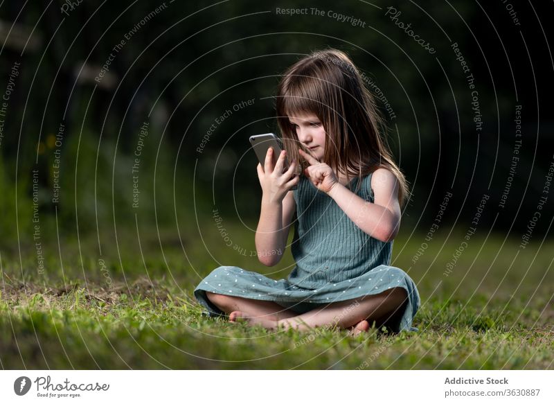 Mädchen surft mit Smartphone im Park erstaunt Schock Überraschung Nachrichten lesen benutzend Rasen Kind Sommer grün Kindheit Kälte Wiese expressiv Unglaube