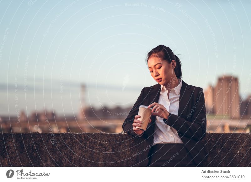 Junge Geschäftsfrau mit einem Kaffee zum Mitnehmen ernst Fokus Frau Imbissbude Pause jung asiatisch ethnisch formal Einwegartikel Tasse Dachterrasse trinken