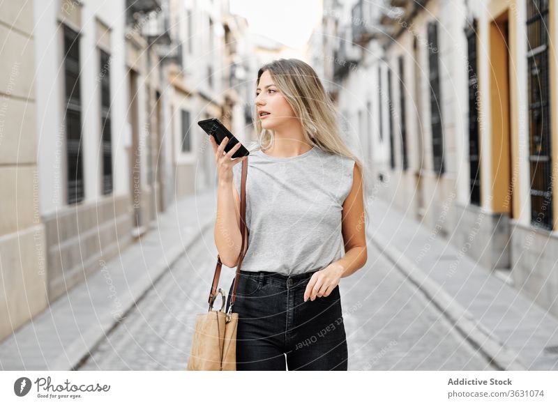 Positive junge Frau mit Smartphone geht auf der Straße Großstadt benutzend Glück Stil Nachricht Spaziergang Browsen Mobile Telefon Lifestyle Gerät Apparatur
