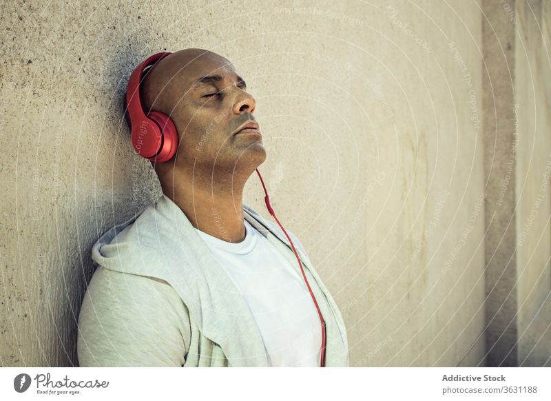 Entspannter Mann hört Musik über Kopfhörer genießen zuhören friedlich sich[Akk] entspannen Harmonie Gesang Großstadt männlich ethnisch Klang Kälte Gerät fettarm
