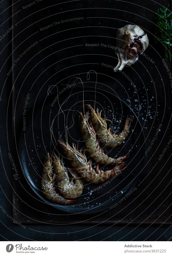 Garnelen im Teller auf Tisch auf dunklem Hintergrund serviert düstere Stimmung Vor dunklem Hintergrund Meeresfrüchte-Platte roher Fisch kalt kulinarisch marin