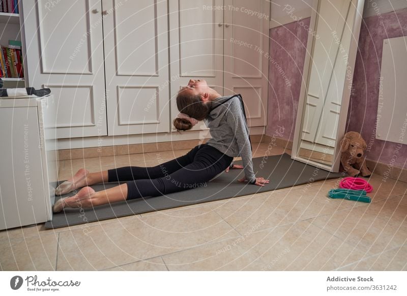 Teenager-Mädchen, das sich im eigenen Zimmer auf einer Matte ausstreckt gymnastisch Dehnung Unterlage heimwärts Kind beweglich Kunst Übung Training dünn