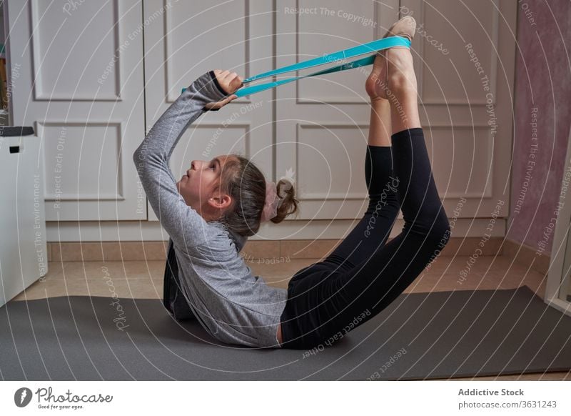 Akrobatisches Mädchen, das mit einem Gummiband die Wirbelsäule dehnt Schleife elastisch gymnastisch Band Dehnung Backend Sportbekleidung Unterlage heimwärts
