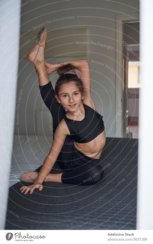 Flexibles akrobatisches Mädchen auf dem Bett sitzend beweglich gymnastisch Bein hinter dem Nacken heimwärts Energie Teenager Gesundheit Aktivität Windstille