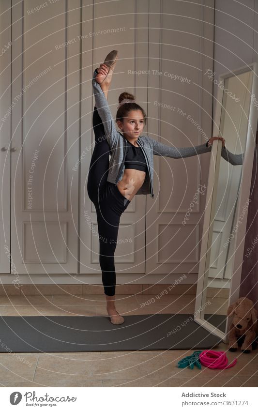 Akrobatisches Mädchen beim Spagat vor dem Spiegel stehend gymnastisch Split Dehnung beweglich heimwärts Bein angehoben schlank Gleichgewicht Tänzer