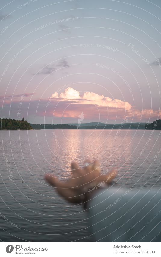 Anonyme Person bewundert Sonnenuntergang über dem See reisen Natur Reisender Wasser Abend Hand Harmonie Freiheit Landschaft romantisch genießen Tourismus