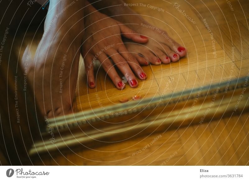 Füße und Hand mit rot lackierten Nägeln vor einem Spiegel rote Nägel Nagellack Pediküre Fußnägel Barfuß feminin Beine Haut Boden Fußboden Zehen Frau Zehennagel