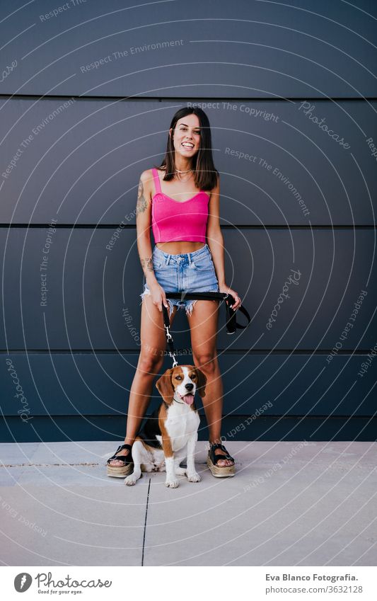 glückliche junge Frau im Freien mit Beagle-Hund. Familien- und Lebensstilkonzept Großstadt urban Lifestyle laufen Freizeitkleidung Kaukasier Sommer Glück