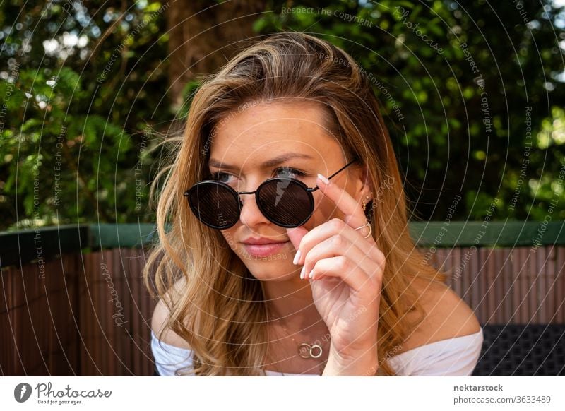 Hübsche blonde Frau mit Sonnenbrille schaut weg Lifestyle Junge Frau Wegsehen Waschtisch abschließen Terrasse Sommer Nur eine Frau kaukasische Ethnizität