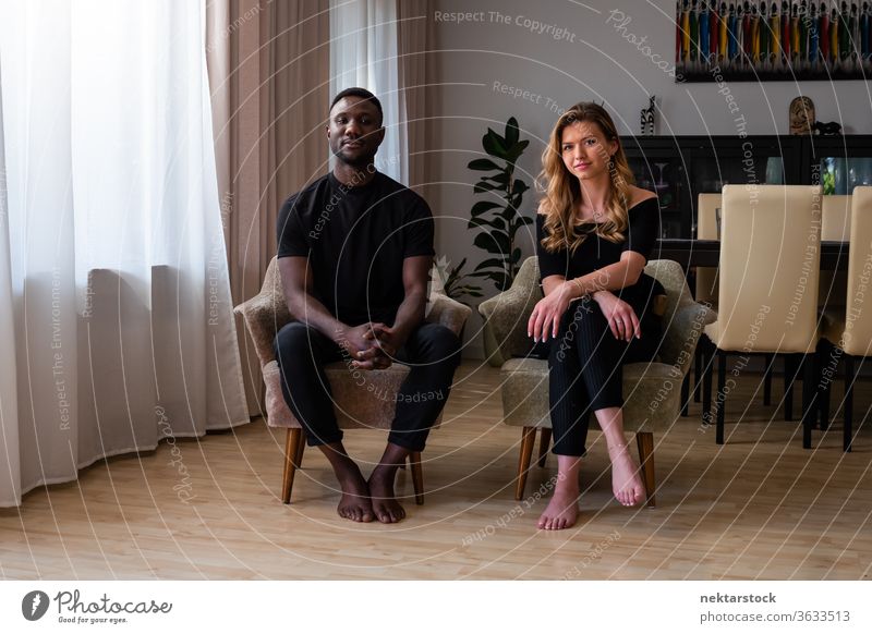 Porträt eines gemischtrassigen Paares in Wohnzimmersesseln sitzend Lifestyle 2 Menschen männlich Frau gemischtrassiges Paar reales Leben echte Menschen