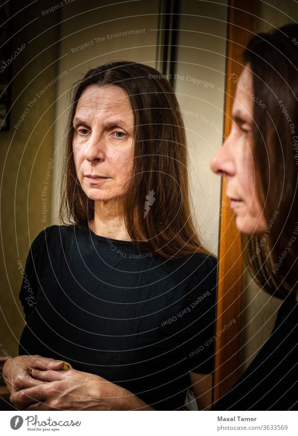 Porträt einer erwachsenen Frau, die sich in einem Spiegel spiegelt 60s häusliches Leben Erwachsener gealtert attraktiv schön Schönheit brünett lässig Kaukasier