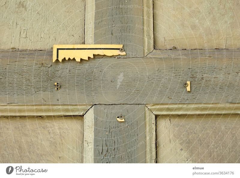 an einer maroden Holztür kann man die Reste eines gelben Schildes erkennen kaputt Kreuz gebrochen broken Hinweis unleserlich Kreuzschraube Hinweisschild