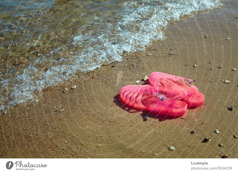 Pink Women's JELLY SANDALS an einer Meeresküste. FLACHE DAMEN-GELEE-SOMMERSTRAND-SCHUHE. Sand Hintergrund Strand hell Küste Farbe farbenfroh bequem Design Mode
