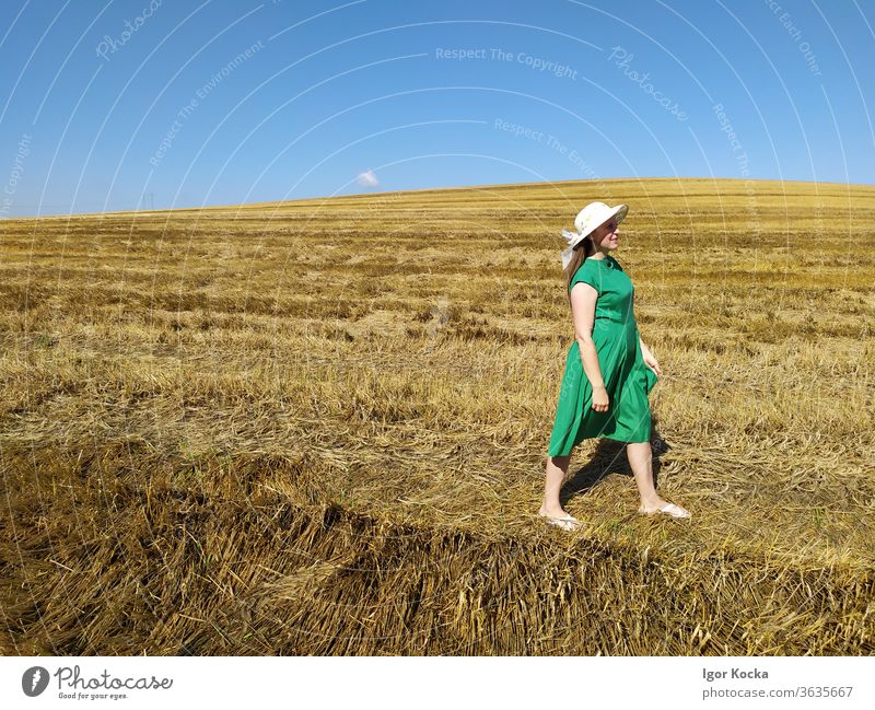 An Land gehende Frau laufen Feld Sommer Klarer Himmel grün Kleid Hut Wiese Landschaft Schönes Wetter Freiheit Lifestyle Textfreiraum