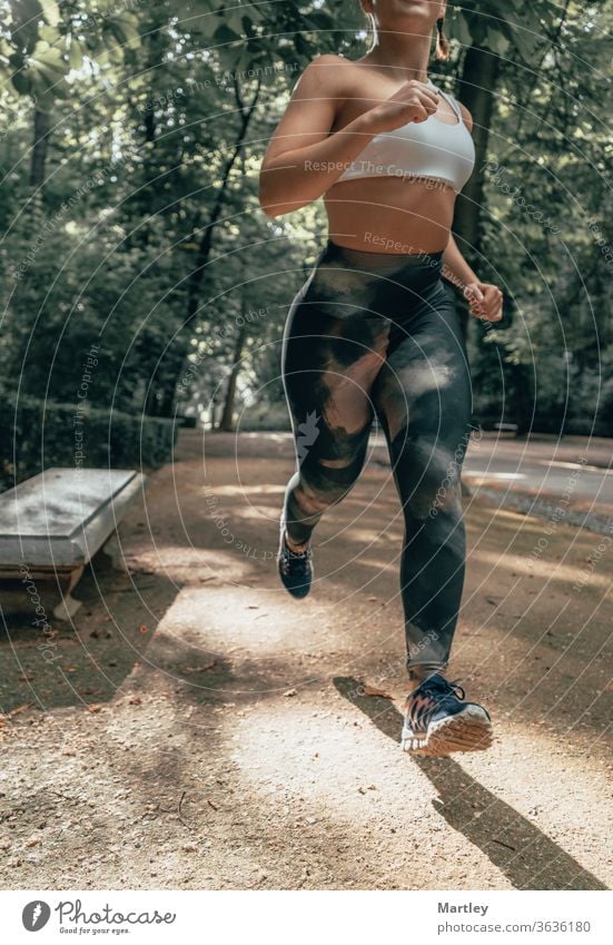 Körper einer fitten Frau, die im Sommer durch einen Park rennt. Fitnessmodel im Freien in der Natur. Konzept des Fitwerdens, Abnehmens und gesunden Lebens