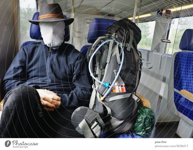 Zugfahrt in Coronazeiten Junger Mann zug fahren Bahn öffentliche Verkehrsmittel sitzen warten Rucksack Rucksacktourismus Maske bedeckung coronavirus Mundschutz